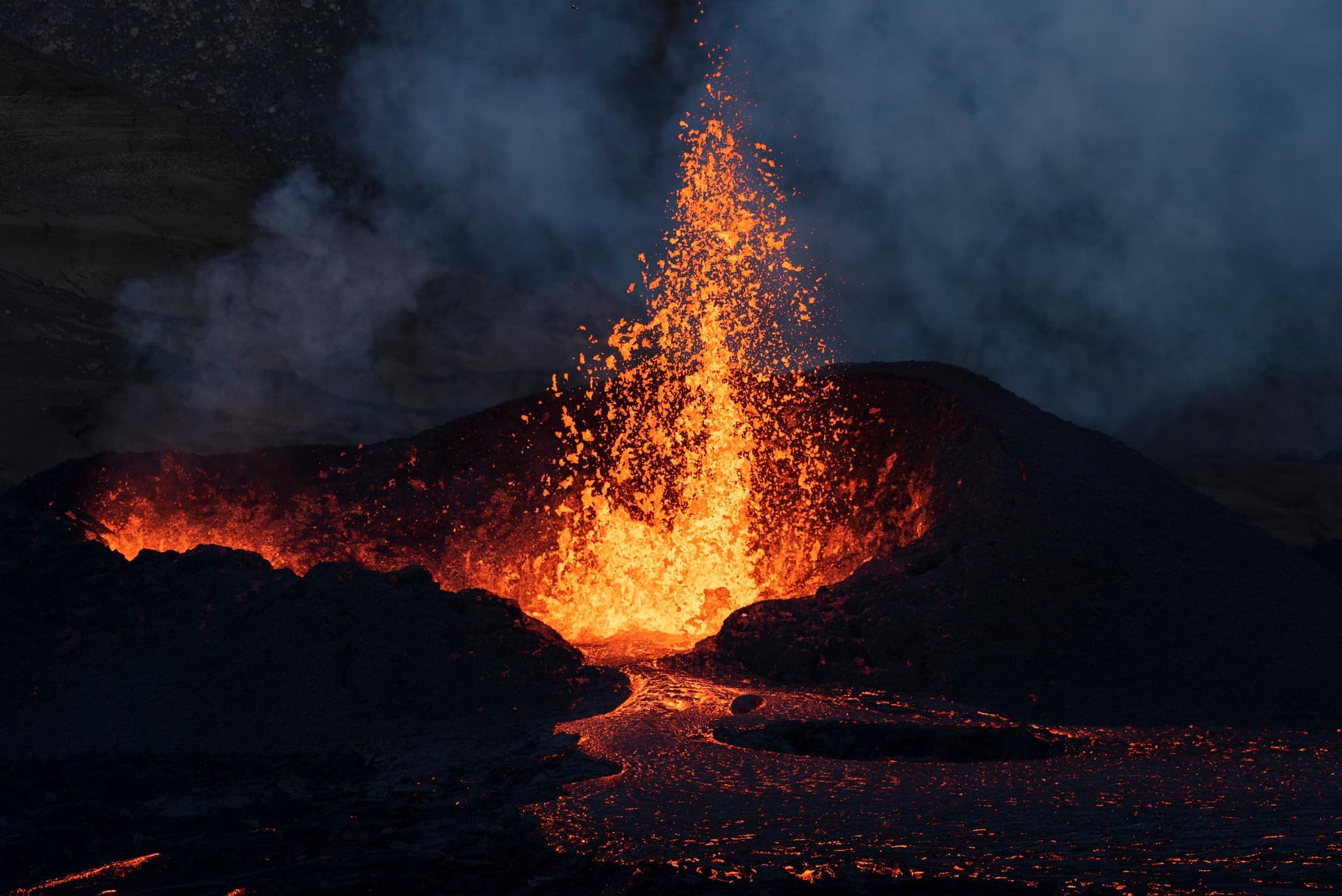 Volcanic landscape with steam rising, suggesting geological and climate stress